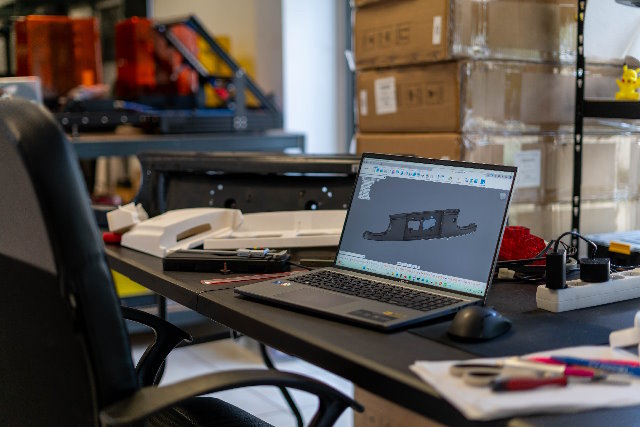 Photo d'une table avec un ordinateur et des morceaux de pièces impression 3D